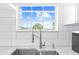 Close-up of kitchen sink featuring a stainless steel faucet and white subway tile backsplash at 8717 Betty St, Port Richey, FL 34668
