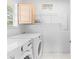 Well-lit laundry room featuring a modern washer and dryer set, complemented by a cabinet and wire shelving at 8717 Betty St, Port Richey, FL 34668