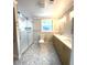 Updated bathroom features a glass-enclosed shower, dual vanities, and stylish tile flooring at 9830 Sheryl Dr, New Port Richey, FL 34654