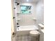 Bright bathroom featuring white subway tiles, decorative floor, and a shower/tub combination with a modern black fixture at 9830 Sheryl Dr, New Port Richey, FL 34654