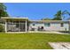 View of backyard featuring screened-in patio, grill, and well-maintained lawn at 6914 N Ola Ave, Tampa, FL 33604
