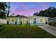 Charming single-story home with well-maintained lawn and landscaping, set against a lovely pink and blue twilight sky at 6914 N Ola Ave, Tampa, FL 33604