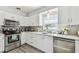 Modern kitchen with stainless steel appliances, white cabinets, gray backsplash, and hardwood floors at 6914 N Ola Ave, Tampa, FL 33604