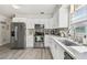 Bright kitchen featuring stainless steel appliances, white cabinets, countertops, and hardwood floors at 6914 N Ola Ave, Tampa, FL 33604
