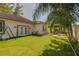 Backyard featuring artificial turf, patio lounge, white fence, and established landscaping at 1150 7Th Ne Ave, Largo, FL 33770