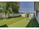 Spacious backyard with lush artificial turf, white fence, and play swing at 1150 7Th Ne Ave, Largo, FL 33770