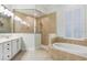 Well-lit main bathroom with tiled tub, tiled shower with glass wall, and dual sinks at 11644 Meridian Point Dr, Tampa, FL 33626