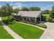 Charming home exterior with a lush green lawn, landscaping, an American flag, and a brick walkway at 12020 66Th Ave, Seminole, FL 33772