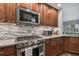 Close-up of stainless steel gas range, microwave, granite countertops, and wood cabinets in kitchen at 12020 66Th Ave, Seminole, FL 33772