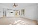 Spacious living room with a view into the kitchen, neutral carpet, and a ceiling fan at 1247 Venetia Dr, Spring Hill, FL 34608