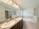 Bathroom features double sinks, soaking tub and walk-in shower with neutral tile at 13181 Royal Pines Ave, Riverview, FL 33579