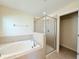 Bathroom featuring a soaking tub, a glass enclosed shower, and neutral tiled walls at 13181 Royal Pines Ave, Riverview, FL 33579