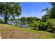 Lush backyard with a serene pond, mature trees, and a cozy seating area at 1393 Chesterfield Dr, Dunedin, FL 34698