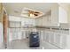 Kitchen awaiting remodel features white cabinets, tile backsplash, and tray ceiling with fan at 1671 Cape Ann Ne Ave # 4, St Petersburg, FL 33702