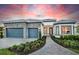 Beautiful home exterior with a lush landscaped yard, stone accents, a gray tiled roof, and a two-car garage at 1845 Ridgemore St, North Port, FL 34289