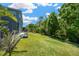 View of the home's sprawling backyard bordered by lush trees on a sunny day at 2321 Wood Pointe Dr, Holiday, FL 34691