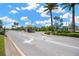 Community entrance road with guard house and palm trees under a partly cloudy sky at 2321 Wood Pointe Dr, Holiday, FL 34691
