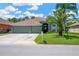 Charming single-story home featuring a three-car garage, a well-manicured lawn, and mature palm trees at 2321 Wood Pointe Dr, Holiday, FL 34691