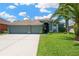 Inviting single-Gathering home featuring a lush lawn, a three-car garage, and meticulously maintained landscaping at 2321 Wood Pointe Dr, Holiday, FL 34691