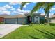 Charming single Gathering home featuring a three car garage, lush lawn and mature landscaping at 2321 Wood Pointe Dr, Holiday, FL 34691