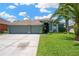 Charming single Gathering home featuring a three car garage, lush lawn and mature landscaping at 2321 Wood Pointe Dr, Holiday, FL 34691