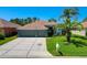 Charming single-story home featuring a three-car garage, a well-manicured lawn, and mature palm trees at 2321 Wood Pointe Dr, Holiday, FL 34691