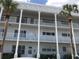 Charming three-story condo with decorative architectural pillars and white railings, complemented by tall palm trees at 2450 Canadian Way # 6, Clearwater, FL 33763