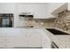 Modern kitchen features granite counters, mosaic backsplash, stainless faucet and white cabinets at 2457 Ecuadorian Way # 63, Clearwater, FL 33763