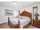 Comfortable bedroom with an intricately carved wooden bed frame, side table, and neutral décor at 2597 Bramblewood E Dr, Clearwater, FL 33763