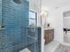 Stylish bathroom boasts blue tiled shower with glass surround, and a modern vanity at 2850 Allapattah Dr, Clearwater, FL 33761