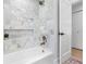 Elegant bathroom features marble tiling in shower/tub area, a plant on shelving, and neutral finishes at 2850 Allapattah Dr, Clearwater, FL 33761