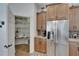 Pantry and stainless steel refrigerator set in wooden cabinetry with granite counters and backsplash at 3060 Sutton Woods Dr, Plant City, FL 33566
