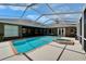 A bright, screened-in pool with a hot tub, brick trim, and a view of the house at 3060 Sutton Woods Dr, Plant City, FL 33566