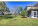 A view of the grassy backyard with a bridge and the screened-in porch of the home at 3292 Covered Bridge E Dr, Dunedin, FL 34698