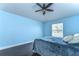 Inviting blue bedroom with hardwood floors, a ceiling fan, and natural lighting at 3292 Covered Bridge E Dr, Dunedin, FL 34698