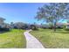 Landscaped walkway through a community featuring manicured lawn, bridge and recreation area at 3292 Covered Bridge E Dr, Dunedin, FL 34698