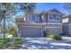 Two-story townhome featuring a two-car garage, neutral paint, and tiled roof and manicured landscaping at 3292 Covered Bridge E Dr, Dunedin, FL 34698