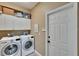 Functional laundry room with modern washer and dryer, ample cabinet space, and exterior door at 3314 Cypress Landing Dr, Valrico, FL 33596