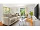 Bright living room featuring a neutral sofa, tropical wallpaper accent, and natural light through the sliding glass door at 4215 E Bay Dr # 1806D, Clearwater, FL 33764