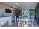 Enclosed patio features an outdoor kitchen with a sink, mini-fridge, and a glass table with chairs at 6328 S Harold Ave, Tampa, FL 33616