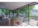 Enclosed patio features a glass table with chairs, brick flooring, and a serene outdoor view at 6328 S Harold Ave, Tampa, FL 33616