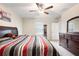 Well-lit bedroom featuring a dresser with mirror, ceiling fan, and a striped comforter at 9617 Channing Hill Dr Dr, Ruskin, FL 33573