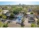 An aerial view showcasing a light blue home with mature trees in a residential area and a partial skyline in the distance at 110 Kenwood Ave, Clearwater, FL 33755