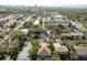 An aerial view showcasing a light blue home with mature trees in a residential area and a partial skyline in the distance at 110 Kenwood Ave, Clearwater, FL 33755