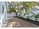 Backyard patio area with brick pavers, framed by a white fence, landscaping and mature trees offering plenty of shade at 110 Kenwood Ave, Clearwater, FL 33755
