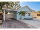 Charming light blue home featuring a quaint front yard and a convenient covered carport with brick driveway at 110 Kenwood Ave, Clearwater, FL 33755