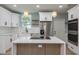 Contemporary kitchen with white cabinetry, stainless steel appliances, and a functional island for culinary enthusiasts at 110 Kenwood Ave, Clearwater, FL 33755