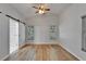 Bright main bedroom featuring a ceiling fan, wood flooring, and a barn door to the bathroom at 11932 Whisper Creek Dr, Riverview, FL 33569