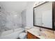 This bathroom features marble-like tiling in the shower and above the bath, plus wood cabinets and a framed mirror at 12351 Ridgedale Dr, Hudson, FL 34669
