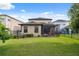 Exterior view of the home featuring a screened-in patio and a spacious green backyard at 17537 Brighton Lake Rd, Land O Lakes, FL 34638